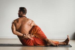 uma homem com uma nu tronco faz ioga dentro de casa. ginástica treinador foto