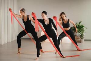 meninas dentro Preto estão fazendo ginástica com vermelho fitas dentro de casa foto