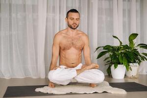 uma homem com uma nu tronco faz ioga dentro uma ginástica sala. a conceito do uma saudável estilo de vida foto