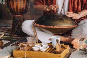 fechar-se do uma do homem mão jogando uma moderno musical instrumento - a orion língua tambor durante a chá cerimônia foto