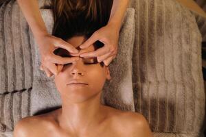 uma cosmetologista menina faz uma facial e pescoço massagem para uma menina dentro a escritório para pele elasticidade foto