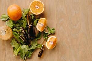 essencial óleo dentro garrafas com a aroma do laranja e hortelã deitado em uma de madeira superfície foto