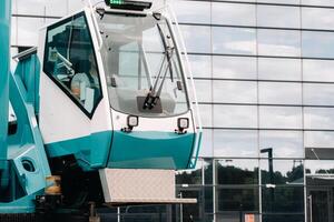 uma táxi com a operador do uma ampla azul carro guindaste este carrinhos pronto para operar em hidráulico apoia em uma plataforma Próximo para uma ampla moderno prédio. a maior caminhão guindaste para resolução complexo tarefas. foto