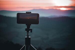 uma Smartphone é gravação a Sol configuração sobre uma montanha faixa. foto