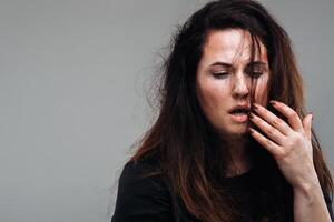 uma maltratado mulher dentro Preto roupas em a isolado cinzento fundo. violência contra mulheres foto