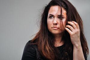 uma maltratado mulher dentro Preto roupas em a isolado cinzento fundo. violência contra mulheres foto