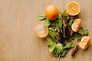 essencial óleo dentro garrafas com a aroma do laranja e hortelã deitado em uma de madeira superfície foto