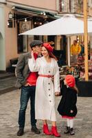 uma à moda família do três passeios através a outono cidade posando para uma fotógrafo . pai, mãe e filha dentro a outono cidade foto