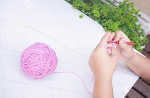 fechar-se do mulher mão tricô com Rosa lã foto