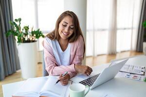 jovem mulher trabalhando computador portátil. o negócio mulher ocupado trabalhando em computador portátil computador às escritório. empresária sentado às brilhante moderno trabalhos estação e digitando em computador portátil foto