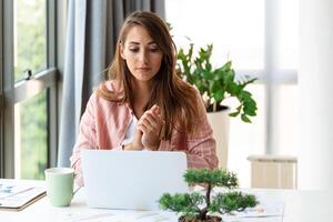 focado o negócio mulher usando computador portátil às lar, olhando às tela, conversando, lendo ou escrevendo e-mail, sentado em sofá, fêmea aluna fazendo trabalho de casa, trabalhando em pesquisa projeto conectados foto