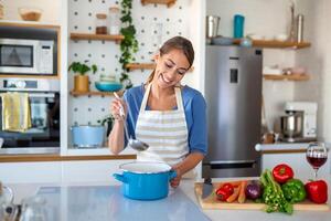 linda jovem senhora dentro uma moderno cozinha, habilmente corte em cubos legumes para crio uma fresco vegetal salada destinada para almoço ou jantar. acionado dentro casa culinária. foto