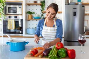 feliz jovem mulher cozinhando degustação jantar dentro uma Panela em pé dentro moderno cozinha às lar. dona de casa preparando saudável Comida sorridente . família e nutrição. dieta receitas conceito foto