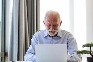 financeiro orientador homem de negocios usando dele computador portátil e fazendo alguns papelada enquanto sentado às escrivaninha e trabalhando. foto