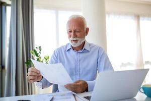 financeiro orientador homem de negocios usando dele computador portátil e fazendo alguns papelada enquanto sentado às escrivaninha e trabalhando. foto