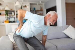 Senior idosos homem tocante dele voltar, sofrimento a partir de dor nas costas, ciática, sedentário estilo de vida conceito. coluna vertebral saúde problemas. assistência médica, seguro foto