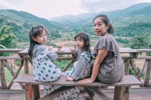 Família feliz e sorridente desfrutando sentado na varanda e olhando as montanhas e o verde foto