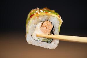 delicioso tradicional japonês Sushi e rolos em uma prato segurando pauzinhos foto