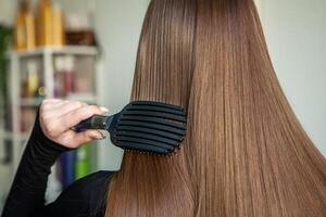 retrato do uma lindo mulher com grandes Castanho em linha reta cabelo dentro uma beleza salão. foto