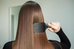 retrato do uma lindo mulher com grandes Castanho em linha reta cabelo dentro uma beleza salão. foto