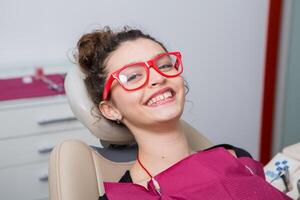 jovem fêmea paciente com bonita sorrir examinando dental inspeção às dentista clínica. saudável dentes e medicamento, estomatologia conceito foto