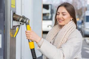 jovem mulher reabastecimento carro com Gasolina às gás estação. eco combustível conceito. a conceito do ambientalmente amigáveis transporte. foto