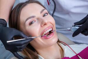 jovem fêmea paciente com bonita sorrir examinando dental inspeção às dentista clínica. saudável dentes e medicamento, estomatologia conceito foto