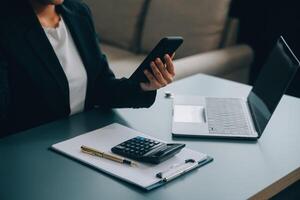 hispânico empresária dentro formal vestuário dentro dela escritório feliz e alegre enquanto usando smartphones e trabalhando. jovem empresária usando apps em célula telefones, lendo notícias, velozes conexão foto