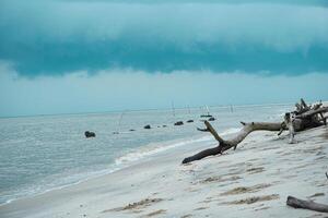 Visão do uma branco areia de praia com nublado clima e céu foto