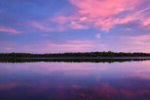 sereno águas uma feliz reflexão do uma lindo pastel lago e céu, Onde tranquilidade encontra da natureza paleta, criando uma harmonioso oásis do suave matizes e etéreo beleza foto
