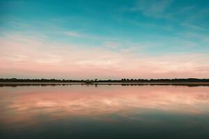 sereno águas uma feliz reflexão do uma lindo pastel lago e céu, Onde tranquilidade encontra da natureza paleta, criando uma harmonioso oásis do suave matizes e etéreo beleza foto