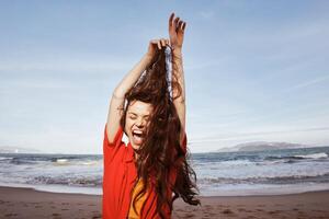 alegre mulher de a mar. sorridente, livre, e radiante dentro vermelho roupas foto