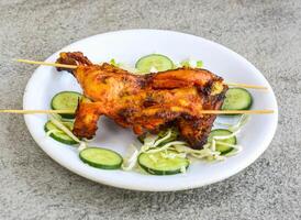 frango tikka perna peça servido dentro prato isolado em cinzento fundo topo Visão do paquistanês e indiano especiarias Comida foto