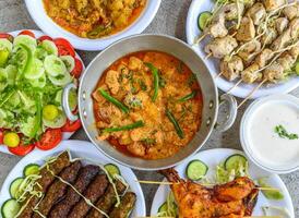 frango desossado mão, karahi, Korma Masala, carne seeh kabab, frango tikka perna pedaço, misturado vegetal, raita e salada servido isolado topo Visão do paquistanês e sortido indiano especiarias Comida foto