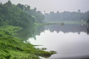 uma panorama Visão do uma calma rio com verde árvores e montanha dentro Índia foto