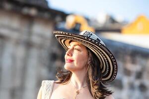 lindo mulher vestindo a tradicional colombiano chapéu chamado sombrero vueltiao às a Paz quadrado em a histórico ruas do a cartagena de índias murado cidade foto