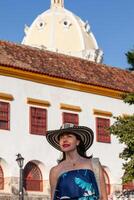 lindo mulher vestindo a tradicional colombiano chapéu chamado sombrero vueltiao às a histórico calle de la ronda do a cartagena de índias murado cidade foto