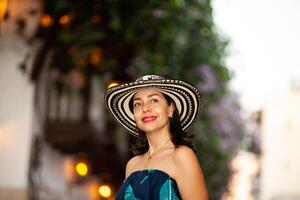 lindo mulher vestindo a tradicional colombiano chapéu chamado sombrero vueltiao às a histórico ruas do a cartagena de índias murado cidade foto