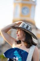 lindo mulher vestindo a tradicional colombiano chapéu chamado sombrero vueltiao às a relógio torre em a histórico ruas do a cartagena de índias murado cidade foto