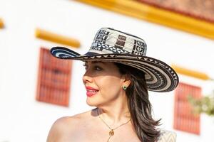 lindo mulher vestindo a tradicional colombiano chapéu chamado sombrero vueltiao às a histórico calle de la ronda do a cartagena de índias murado cidade foto