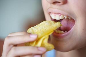 irreconhecível Adolescência menina comendo crocante batata salgadinhos às casa foto