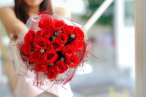 mulher detém ramalhete do vermelho rosas dentro dela mão depois de recebendo 1 a partir de dela namorado em dia dos namorados dia para mostrar dele amor para mulher. enviando ramalhete do rosas para seu amante para expressar seu amor para cada foto