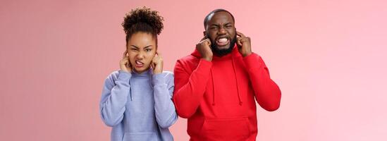 irritado irritado casal africano americano irmãos homem mulher encolhendo-se desconforto fechar orelhas plugue dedos não ouvir Terrível repugnante ruído em pé incomodado fazendo careta ouvir horrível som foto