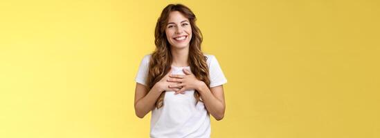 menina agradecendo de bom grado impressionante oportunidade parte do equipe sorridente grato pressione Palmeiras coração sorrindo inclinar cabeça adorável divertido grato olhar Câmera Deleitado ficar de pé amarelo fundo foto