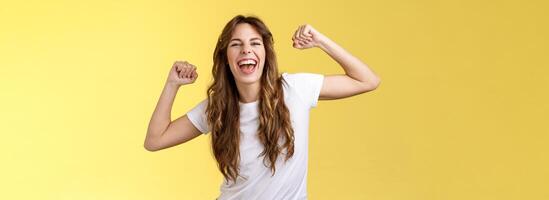 menina obrigado convite impressionante festa tendo Diversão ir selvagem levantar mãos acima relaxado solto dançando lábio sincronizar legal música desfrutando momento vestem branco camiseta casual equipamento a comemorar amarelo fundo foto