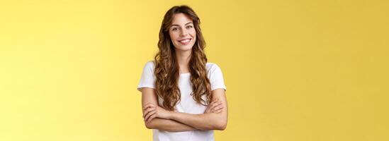 confiante despreocupado animado sorridente fêmea trabalhador autonomo profissional Cruz braços peito confiante pose ficar de pé confortável branco camiseta sorrindo cheio de dentes Deleitado ficar de pé amarelo fundo amigáveis foto