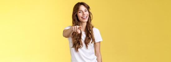 Ei você parabéns. alegre boa aparência amigáveis entusiasmado adorável menina rindo alegremente apontando Câmera brincadeira colheita fazer escolha felicitar excelente trabalho ficar de pé amarelo fundo sorridente foto