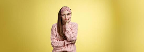 quão tedioso. indiferente chateado sombrio menina ausência de festa sentindo-me entediado inclinado em Palma relutante, triste olhando descuidado às Câmera visitando desinteressante palestra, sofrimento tédio sobre amarelo parede foto