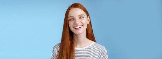 feliz amigáveis carismático alegre jovem sincero 20s ruiva menina tendo Diversão sorridente alegre rindo brincadeira falando casualmente sorrindo Câmera expressar positivo por sorte atitude, em pé azul fundo foto