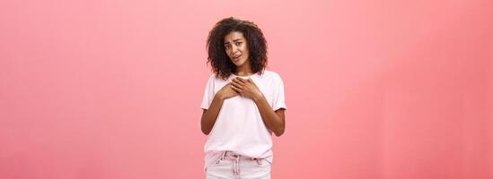 oh você fundição meu coração tão doce. tocou e grato boa aparência Encantado africano americano mulher com encaracolado cabelo dentro à moda equipamento segurando Palmeiras em coração suspirando a partir de deleite e grato sentimentos foto